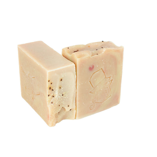 September Sun artisan soap by Don Gato Soap Co., two cream-colored bars with dark speckles and an embossed cat-in-top-hat stamp, in bright light on a white background.