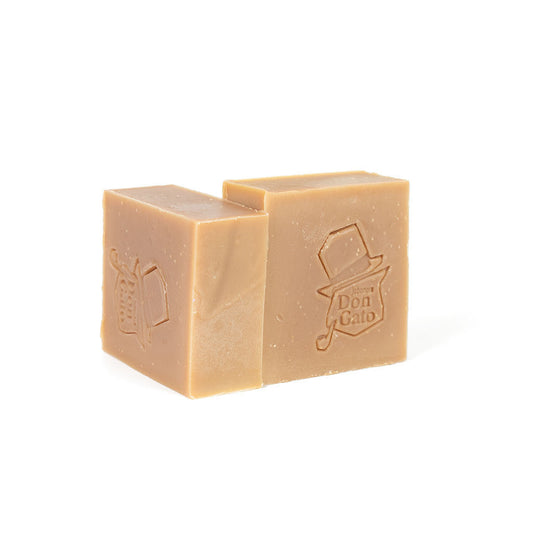 The Enchantress artisan soap by Don Gato Soap Co., two warm tan bars with an embossed Don Gato cat-in-top-hat stamp, in bright light on a white background.